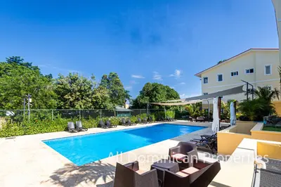 a swimming pool in a yard with chairs and a building at Hill Side Condos - Hispaniola in Sosúa