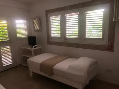 a bedroom with a bed and a chair and windows at Hotel Casa Robinson in Las Terrenas