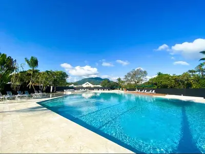 a large swimming pool with chairs and trees at Apartamento de playa in San Felipe de Puerto Plata