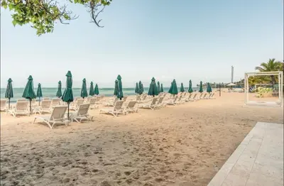a group of chairs and umbrellas on a beach at Apartamento de playa in San Felipe de Puerto Plata