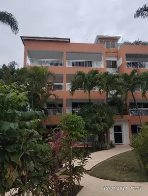 an orange building with palm trees in front of it at Residencial caoba in Las Terrenas