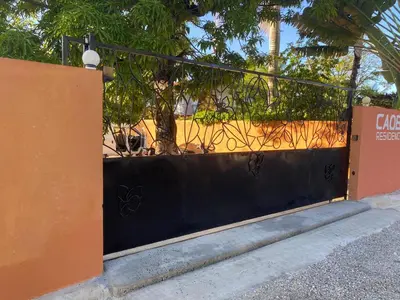 a black and orange fence with a tree behind it at Residencial caoba in Las Terrenas