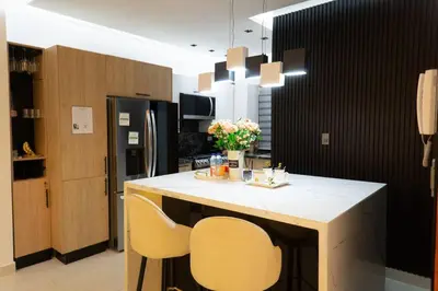 a kitchen with a counter with two chairs and a refrigerator at Acogedor y exclusivo Apt en el gran Santo Domingo in Santo Domingo