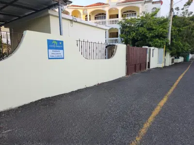 a white fence next to a street with a house at Costambar Ocean Breeze - Beachfront Apartment with Pool in San Felipe de Puerto Plata