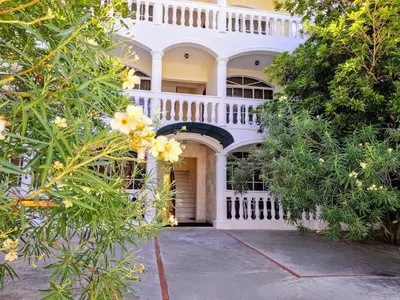 a white house with a white fence and flowers at Costambar Ocean Breeze - Beachfront Apartment with Pool in San Felipe de Puerto Plata