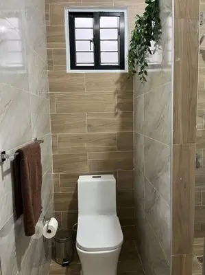 a bathroom with a white toilet and a window at Cozy Apartment in the heart of Santiago in Santiago de los Caballeros