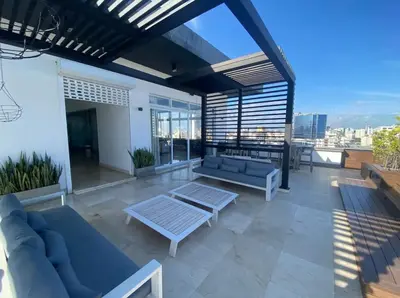 a patio with couches and a table on a roof at PiantiniTowerCentric SDQ CityView in Santo Domingo