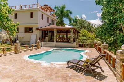 a pool with a chair and a house at Exclusive Mountain Villa with Ocean View near Puerto Plata in Maimón