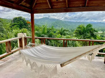 a hammock on a porch with a view of the mountains at Exclusive Mountain Villa with Ocean View near Puerto Plata in Maimón