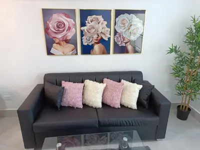 a living room with a black couch with pink and white pillows at Boca del Mar III, apto 707 in Boca Chica