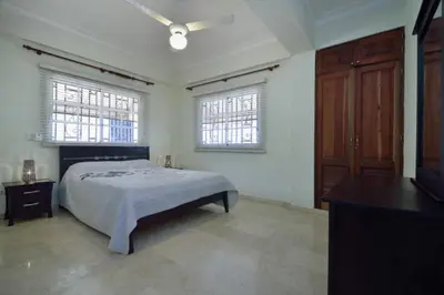 a bedroom with a bed and a dresser and two windows at Comfortable Apt Laura Virginia in Santo Domingo in Santo Domingo