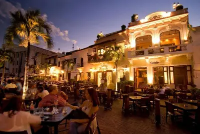a group of people sitting at tables in front of a building at Comfortable Apt Laura Virginia in Santo Domingo in Santo Domingo