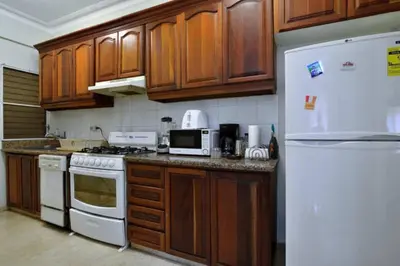 a kitchen with wooden cabinets and a white refrigerator at Comfortable Apt Laura Virginia in Santo Domingo in Santo Domingo