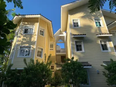 a large yellow building with trees in front of it at Playa Las Ballenas Oceanfront in Las Terrenas
