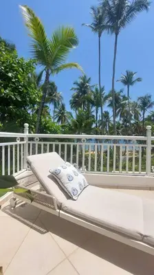 a white chaise lounge on a patio with palm trees at Playa Las Ballenas Oceanfront in Las Terrenas