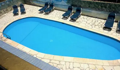 a swimming pool with chairs and blue water at Hotel Angel Gabriel in Boca Chica