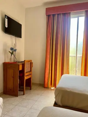 a bedroom with a bed and a desk and a window at Hotel Angel Gabriel in Boca Chica