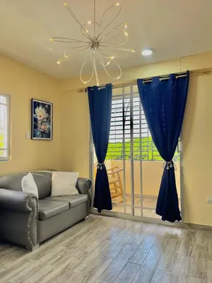 a living room with a couch and blue curtains at Acogedor apartamento in Azua de Compostela