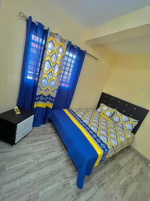 a bedroom with a bed with blue and yellow sheets and a window at Acogedor apartamento in Azua de Compostela