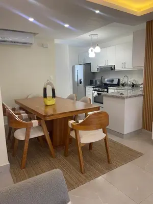 a kitchen and dining room with a wooden table and chairs at Hermoso apto amueblado a 5 minutos de downtown Punta Cana in Punta Cana