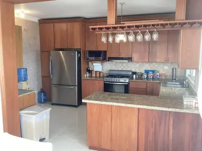 a kitchen with wooden cabinets and a stainless steel refrigerator at Apartment with ocean front view in Juan Dolio