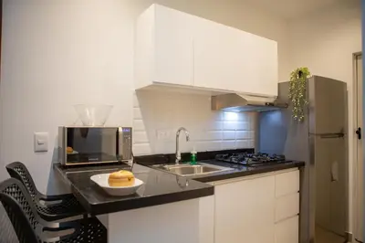 a kitchen with white cabinets and a sink and a microwave at Las Golondrinas Cabarete in Cabarete