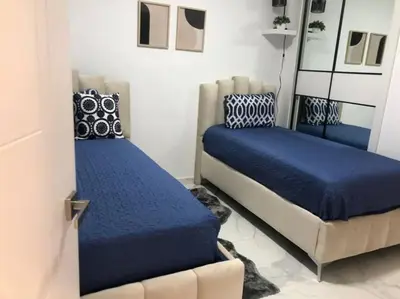 a bedroom with two beds with blue covers and a door at The Peña family suite in Punta Cana
