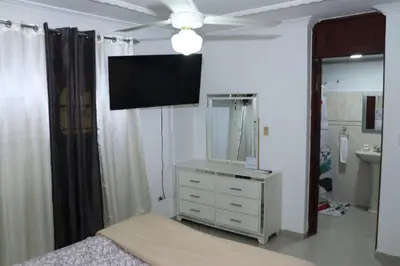 a bedroom with a television and a dresser with a mirror at Three-Bedroom Apartment 3 in Santo Domingo