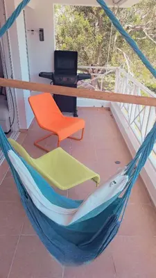 a hammock on a balcony with a chair and a computer at guababerry Juan dolio in Los Conucos