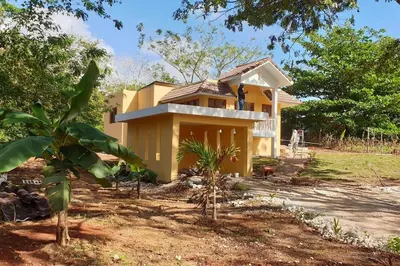 a yellow house in the middle of a yard at Villa LiMar in Río San Juan
