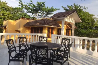 a table and chairs on a porch with a house at Villa LiMar in Río San Juan