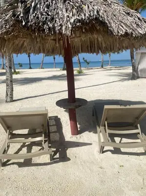 two chairs under a straw umbrella on the beach at Apartment in Playa Nueva Romana in San Pedro de Macorís