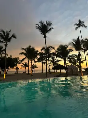 a swimming pool with palm trees and a beach at Apartment in Playa Nueva Romana in San Pedro de Macorís