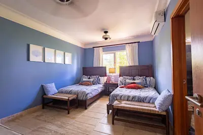 a blue room with two beds and a chair at Sunset Cove at Balcones in Las Terrenas