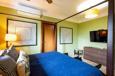 a bedroom with a blue bed and a flat screen tv at Sunset Cove at Balcones in Las Terrenas