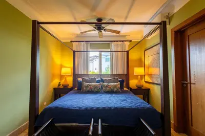 a bedroom with a blue bed with a ceiling fan at Sunset Cove at Balcones in Las Terrenas