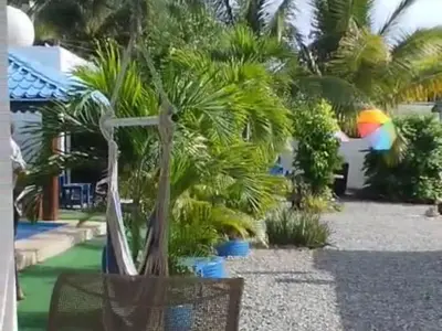 a palm tree with a rainbow umbrella in a yard at Villa Luz in Andrés