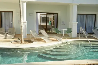 a pool with chairs and a table in a building at Bahia Principe Luxury Esmeralda All Inclusive - Newly Renovated in Punta Cana