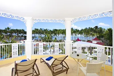 a balcony with chairs and a table and a view of the ocean at Bahia Principe Luxury Bouganville - Adults Only All Inclusive in La Romana