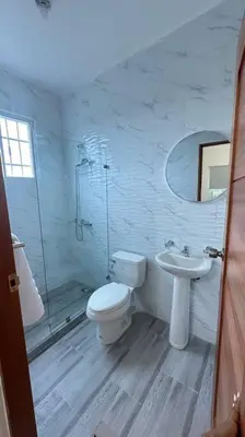 a white bathroom with a toilet and a sink at Hospedaje Lujoso en Boca Chica in Santo Domingo