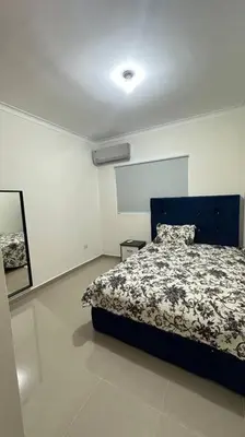 a bedroom with a blue bed in a white room at Hospedaje Lujoso en Boca Chica in Santo Domingo
