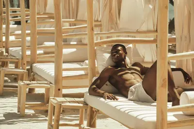 a shirtless man laying on bunk beds on the beach at Cayo Levantado Resort - All Inclusive in Santa Bárbara de Samaná