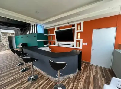 a office with a bar with stools and a tv at Apartamento lujoso y cómodo in Santo Domingo