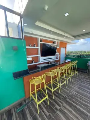 a room with a bar with chairs and a flat screen tv at Apartamento lujoso y cómodo in Santo Domingo
