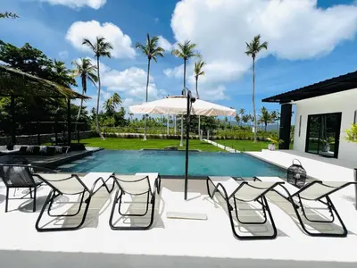 a pool with chairs and an umbrella and palm trees at Casa B&W, Villa luxueuse Exceptionnelle, 8 personnes, à 1 min de la plage in Las Galeras