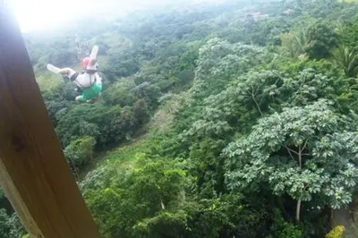 a person flying in the air over a forest at Brand New beach and golf condo in Punta Cana in Punta Cana