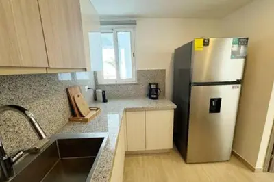 a kitchen with a stainless steel refrigerator and wooden cabinets at Brand New beach and golf condo in Punta Cana in Punta Cana