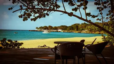 a table and chairs sitting next to a beach at Hispaniola Luxury Ocean Front Condo in Sosúa