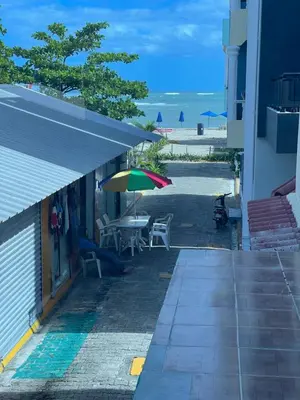 a patio with a table and an umbrella and the beach at Tiny Home-El Pueblito in San Felipe de Puerto Plata
