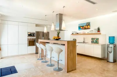 a kitchen with white cabinets and a counter with stools at New private luxury villa in Punta Cana in Punta Cana